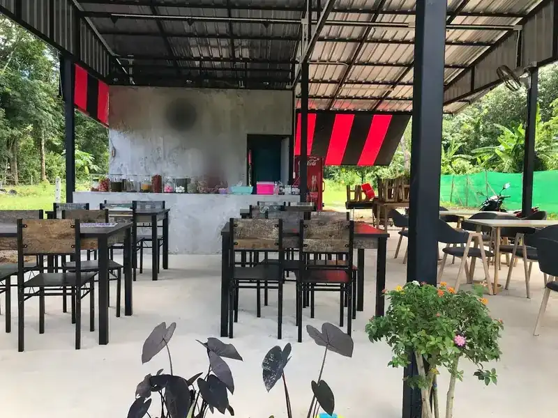 Tables under the open-sided tin roof, with the counter at the back