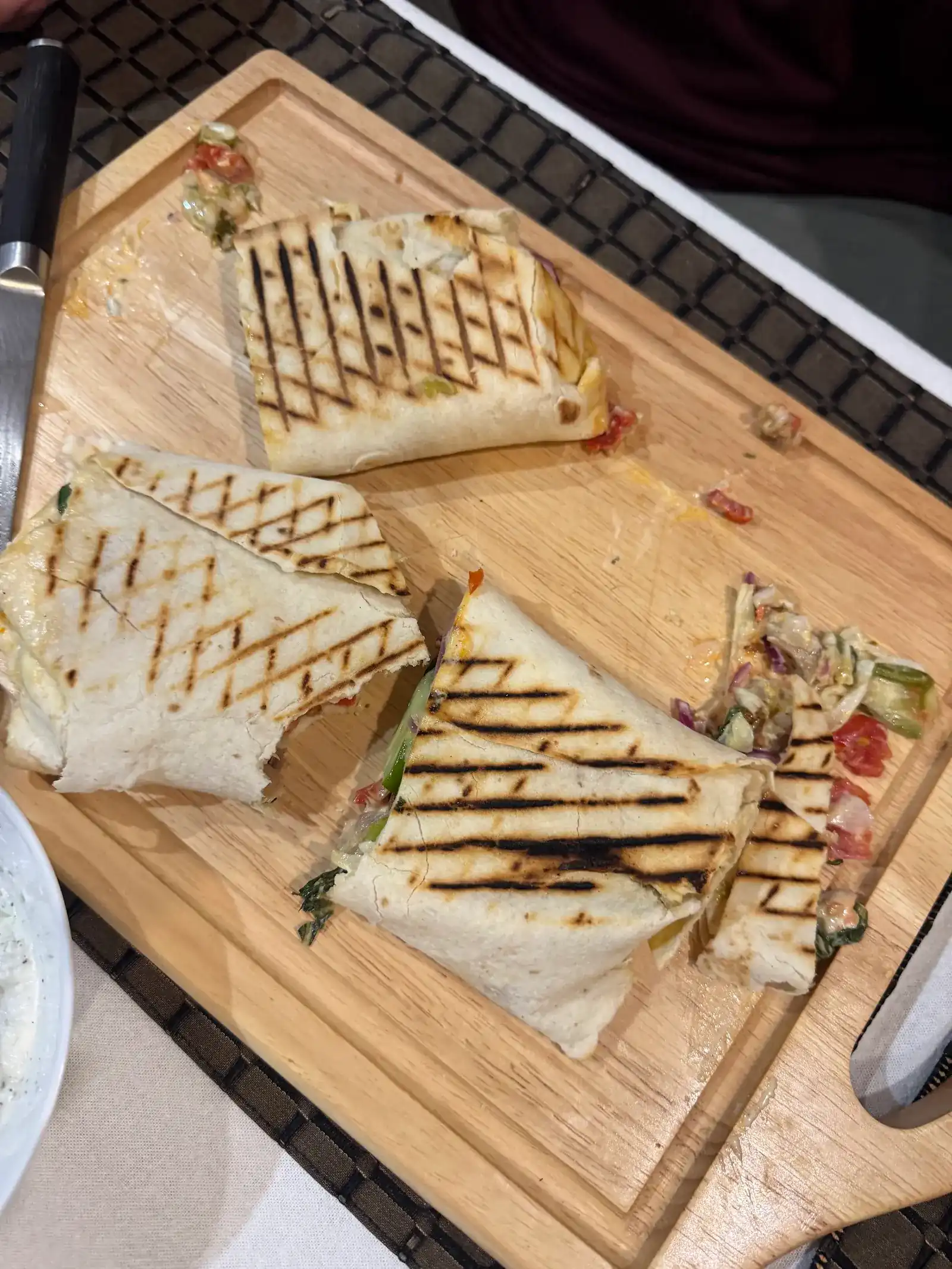 Grilled shawarma wraps cut in half on a wooden board, criss-cross grill marks on the lavash