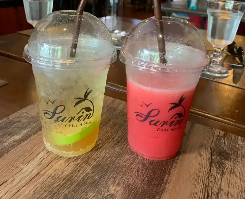 Two cold drinks, one green and one red, in Surin Chill House cups