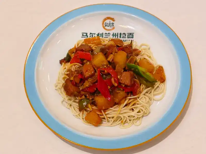 Noodles with a stir-fried topping of potato and red and green peppers on a plate printed 马尔利兰州拉面