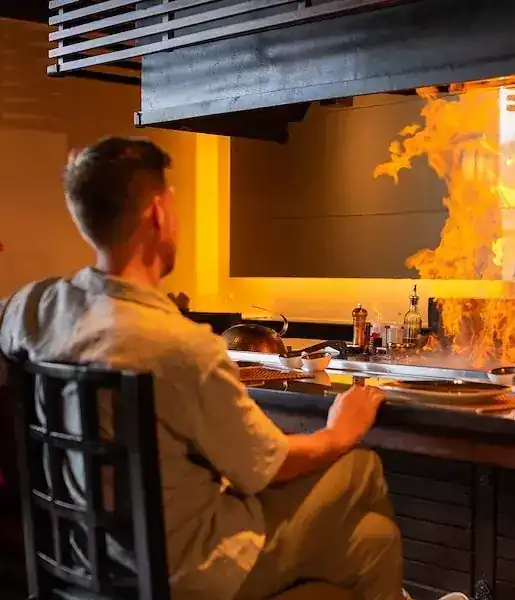 A guest at the teppanyaki counter, facing a wall of flame