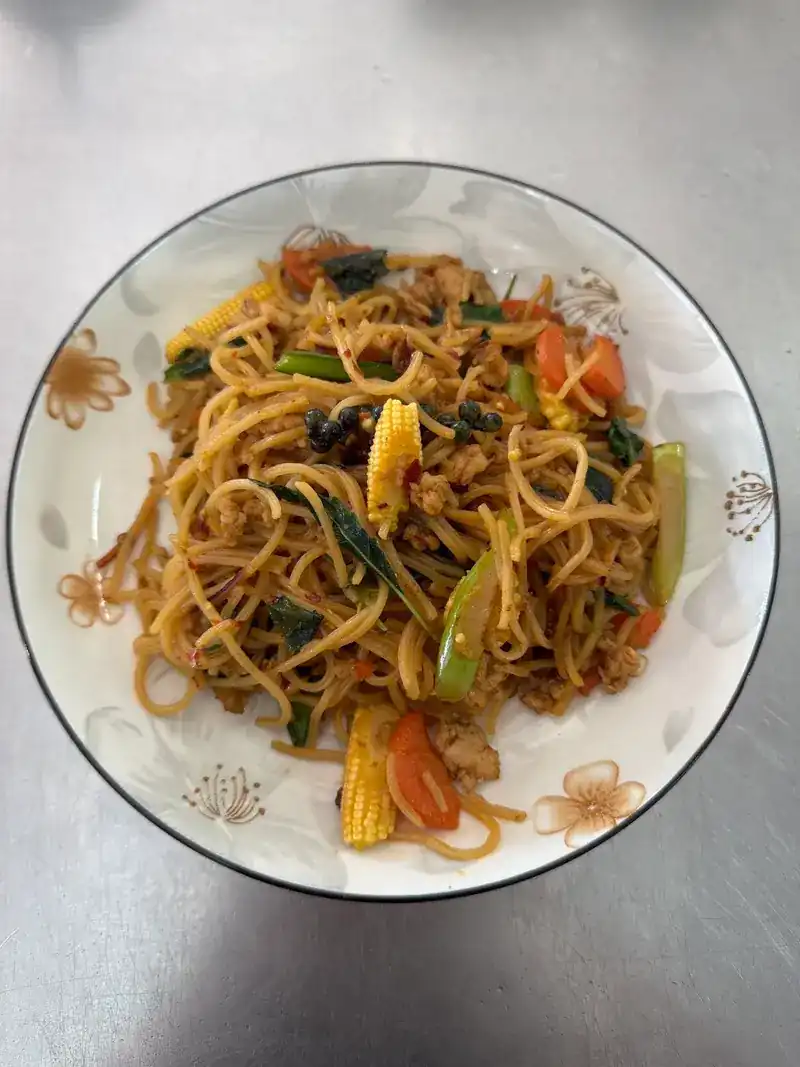 Stir-fried noodles with baby corn, tomato and greens