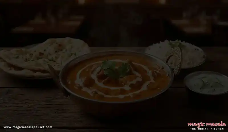 A curry with a swirl of cream in a metal kadhai, with naan and rice