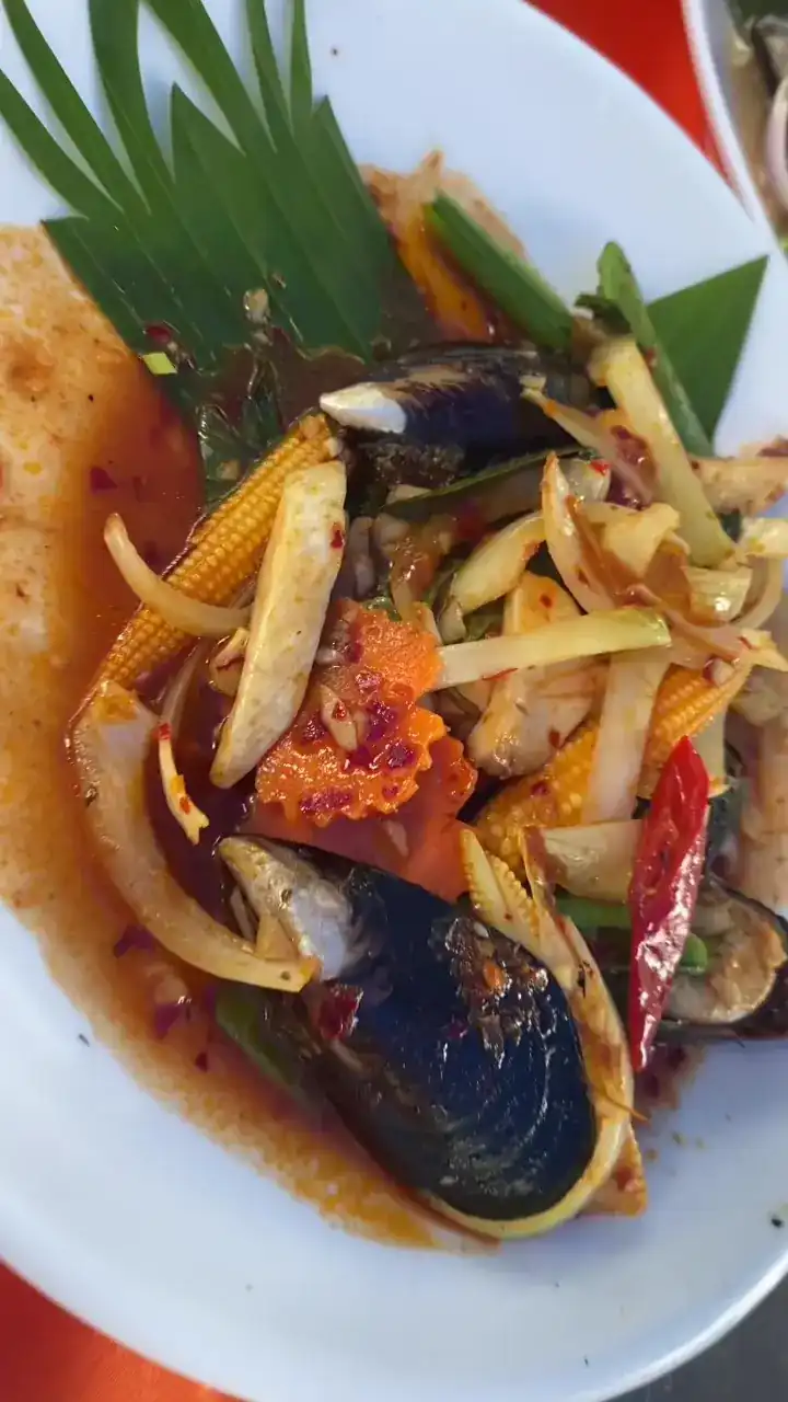 Mussels with chilli, onion and baby corn on a white plate