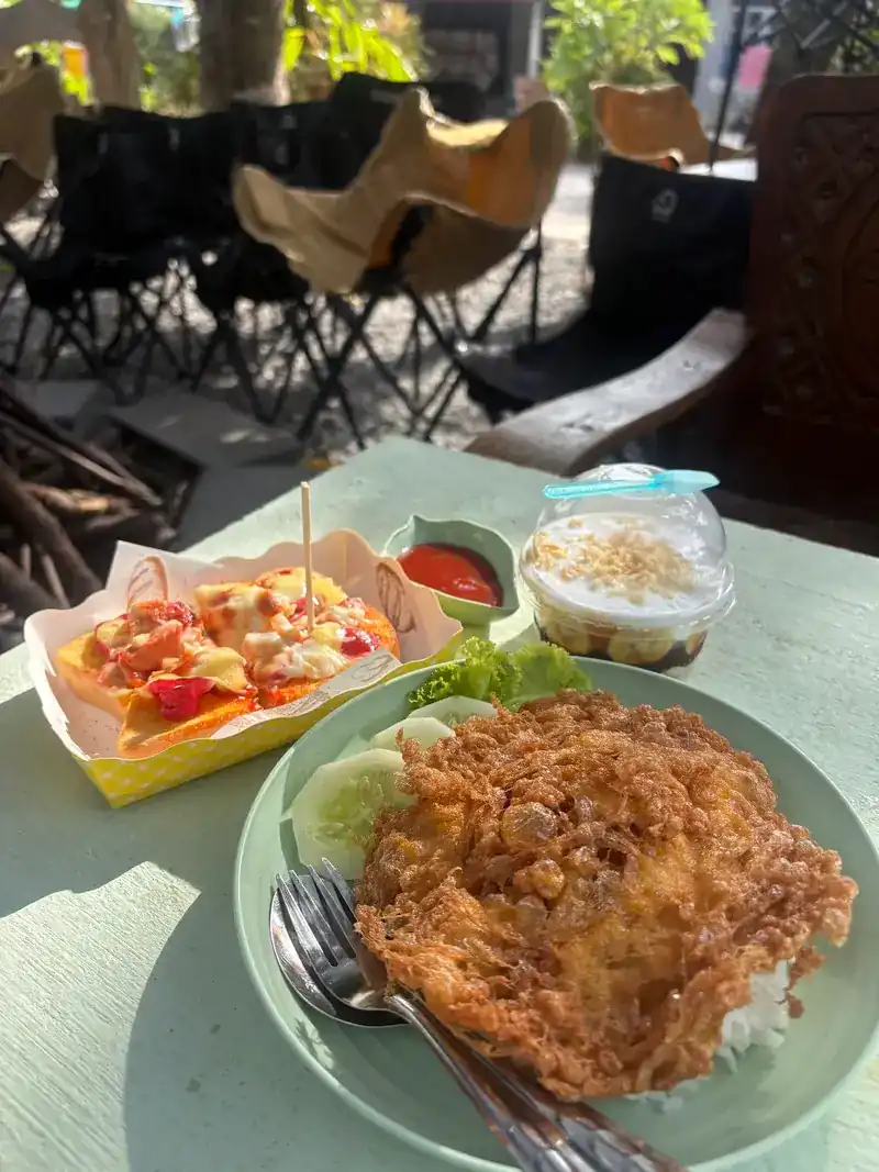 A crispy omelette over rice with cucumber, on a table in the garden