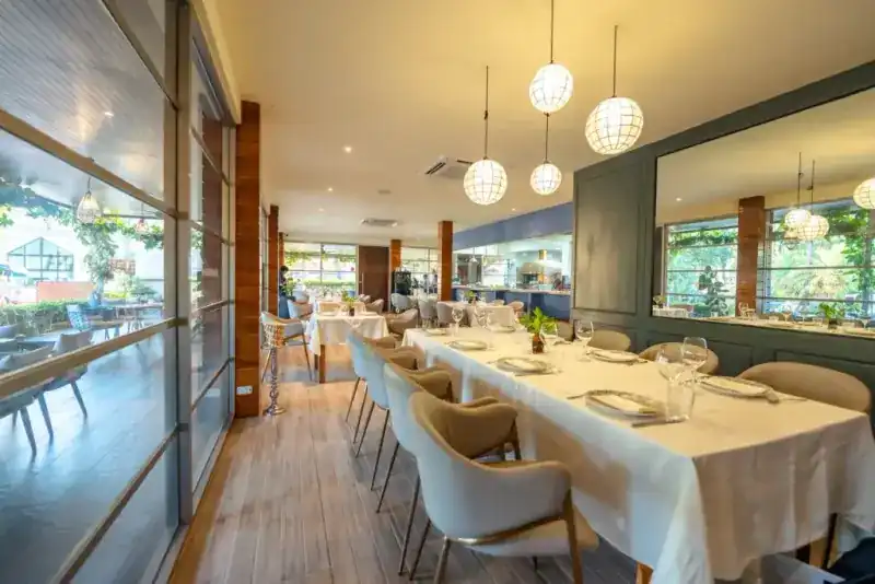 Long tables under paper lanterns, with the kitchen at the far end of the room