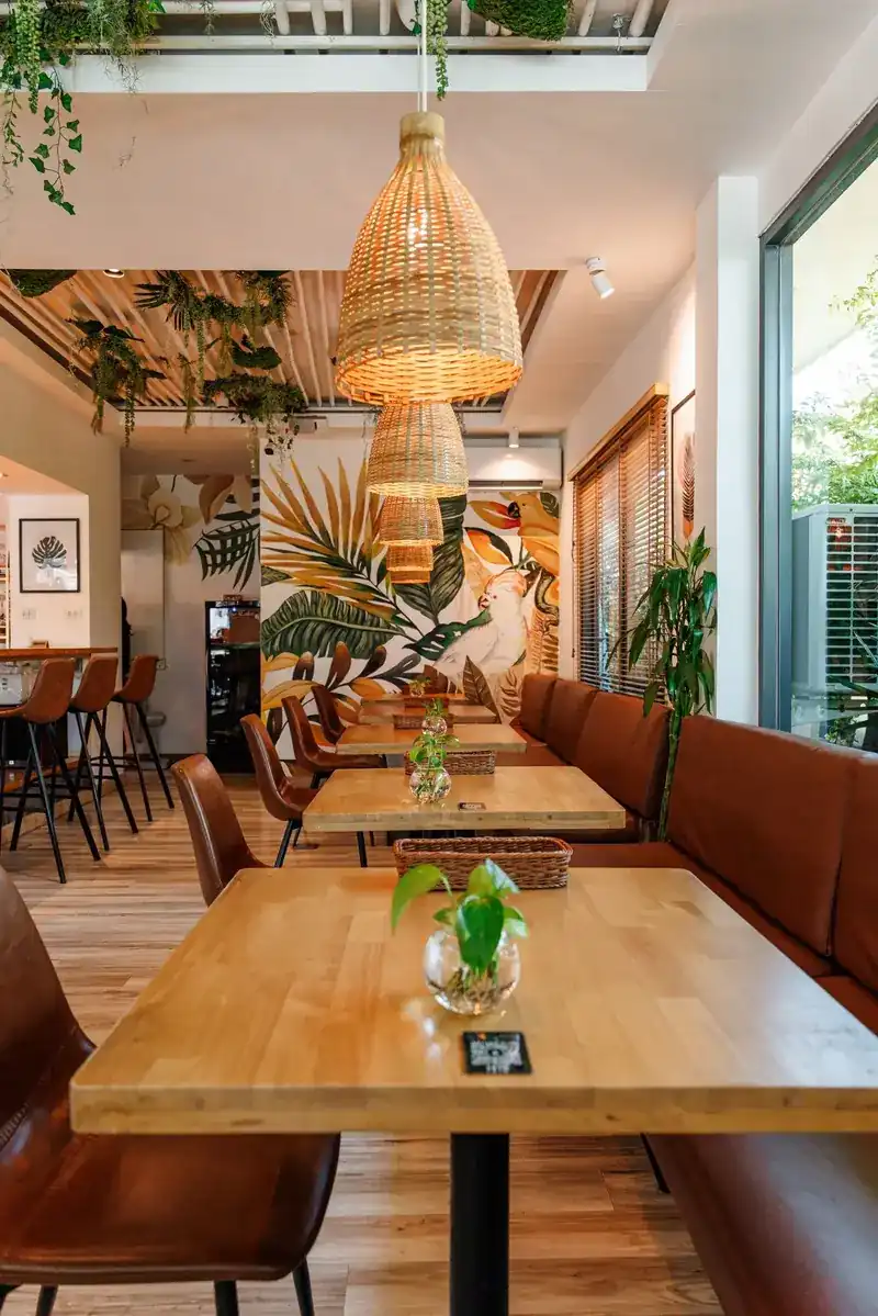 The dining room at BOOST: wooden tables, tan leather benches, rattan lamps and a tropical mural