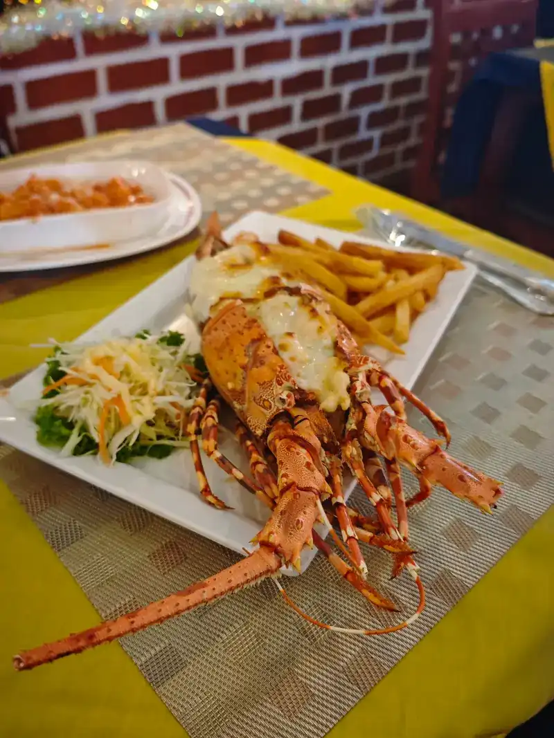 Halved lobster with fries and salad on a yellow tablecloth