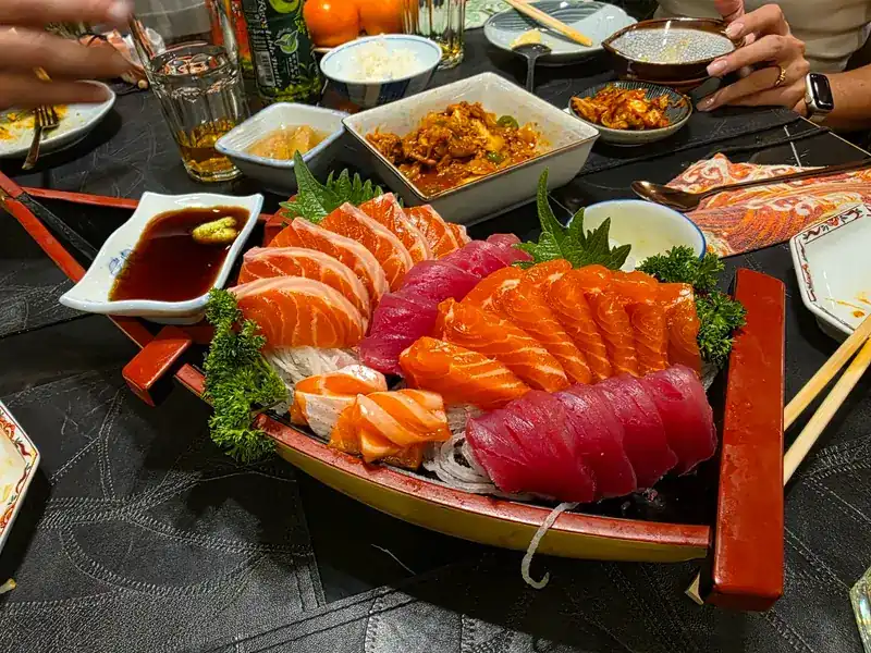 Salmon and tuna sashimi on a wooden boat, with soy sauce and wasabi
