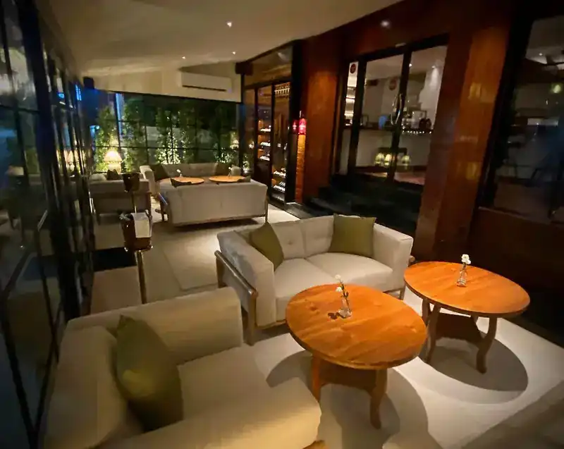 The welcome lounge at night, with cream sofas and round wooden tables