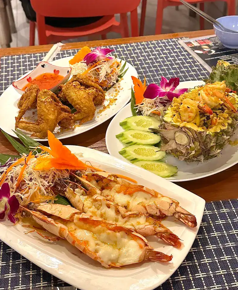 Prawns baked with cheese, fried chicken wings and pineapple fried rice on one table / กุ้งอบชีส ปีกไก่ทอด และข้าวผัดสับปะรดบนโต๊ะเดียวกัน