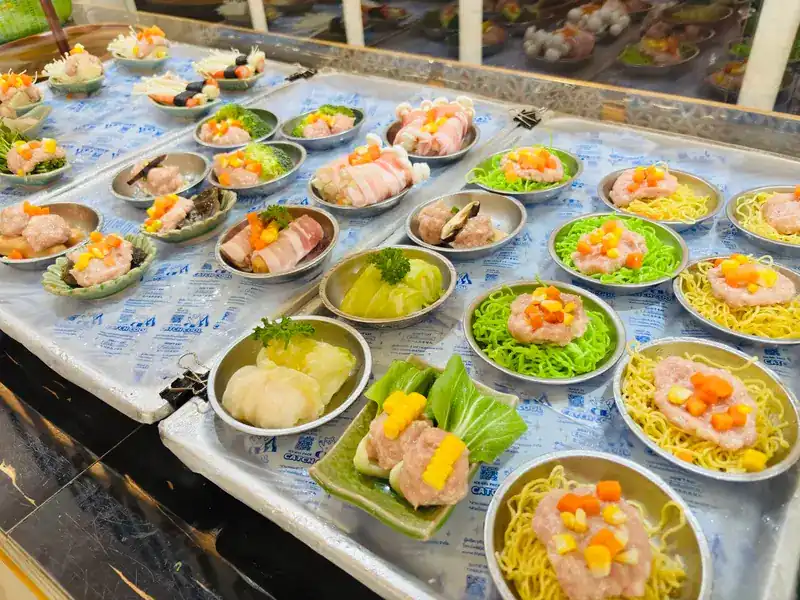 Plates of dim sum laid out on the counter, some on yellow and green noodles