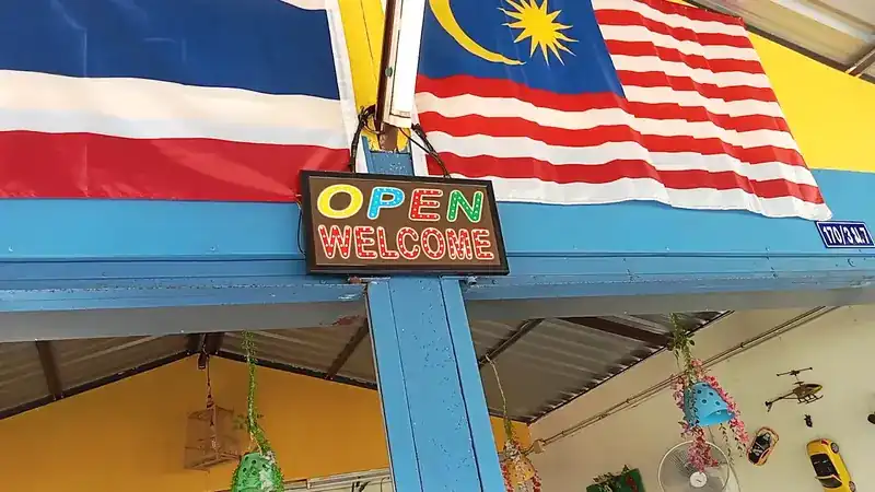 Thai and Malaysian flags over the front, with an Open Welcome sign / ธงชาติไทยและธงมาเลเซียเหนือหน้าร้าน กับป้ายต้อนรับ