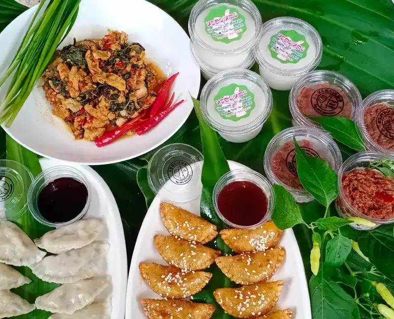 A spread from the kitchen: a spicy stir-fry, steamed dumplings, fried pastries with sesame, dipping sauces and cups with the shop’s label