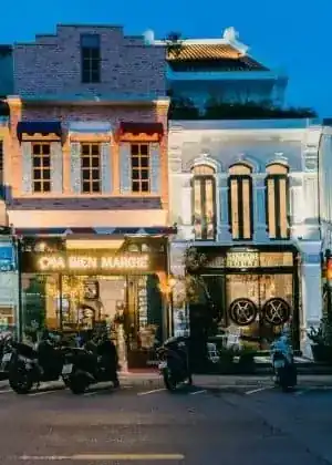 The restaurant's shophouse front on Dibuk Road at dusk, its sign lit above the doorway