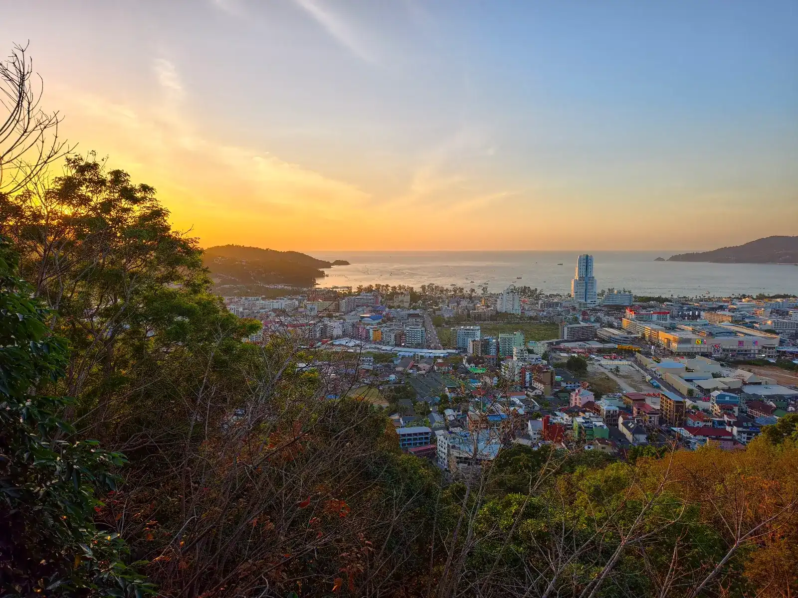 Sunset over Patong Bay seen from the hill, the town and the sea below