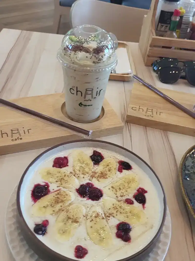 A bowl topped with banana and berries, with a blended drink behind it