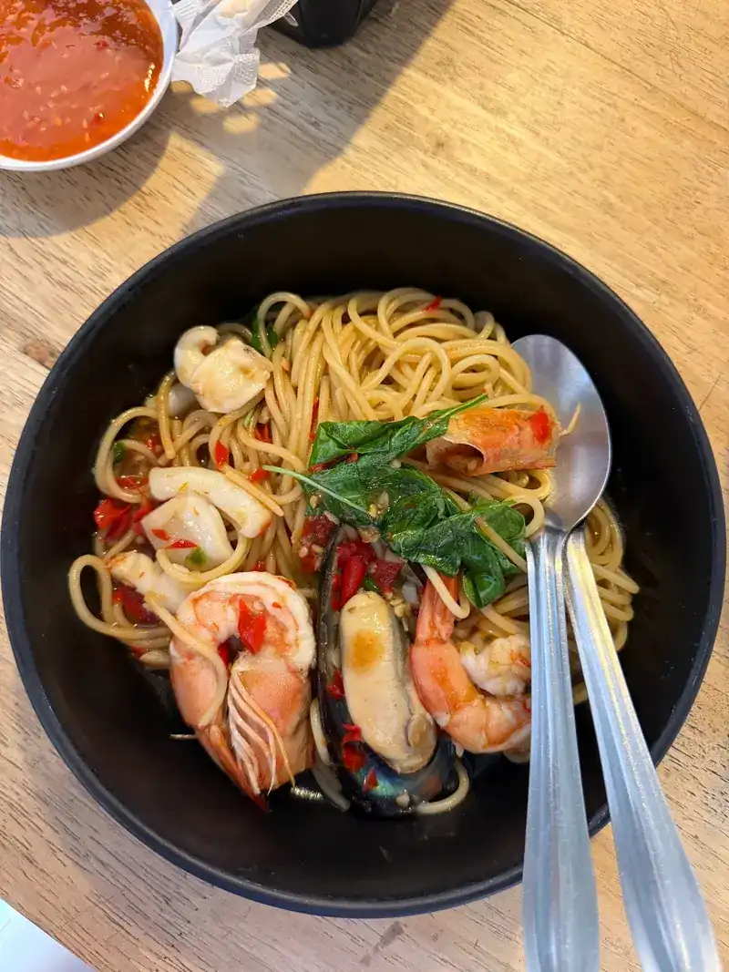 Spaghetti with prawns, squid, mussels and red chilli in a dark bowl / สปาเกตตีกับกุ้ง หมึก หอยแมลงภู่ และพริกแดงในชามสีเข้ม
