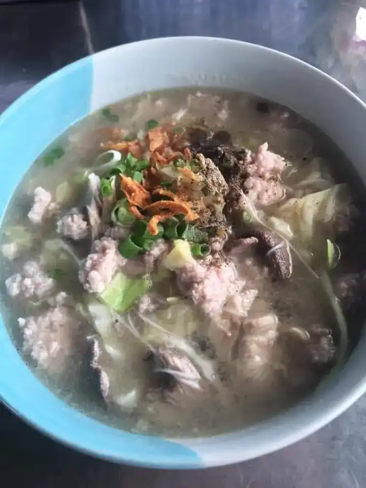 A bowl of hot soup topped with fried garlic and spring onion