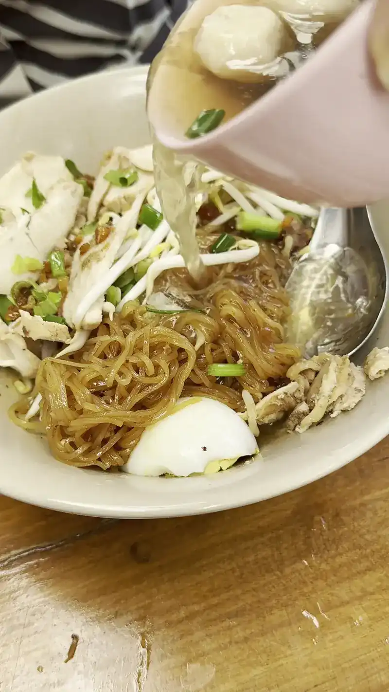 Broth poured over a bowl of noodles with chicken and egg / ราดน้ำซุปลงบนก๋วยเตี๋ยวไก่ใส่ไข่