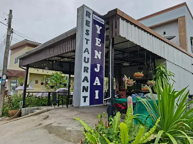 Yenjai's open-sided dining room, its tall purple sign and a garden of potted plants