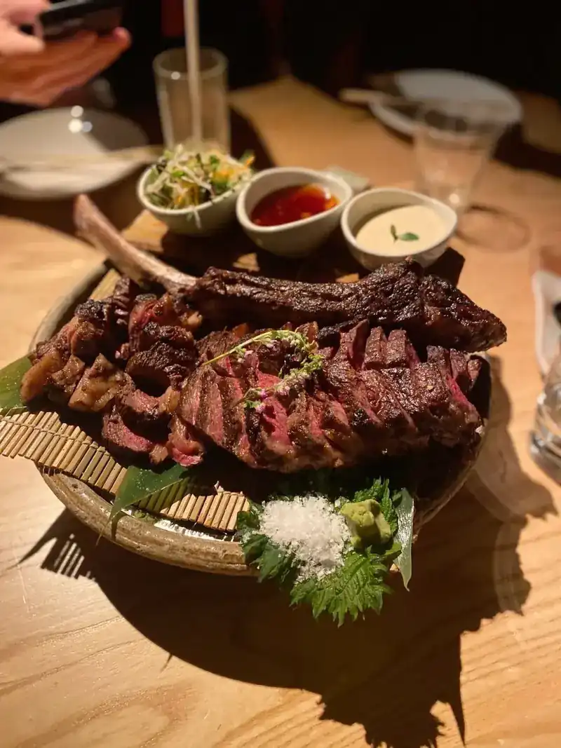 Beef on the bone, sliced and served on a wooden board with three dipping sauces / เนื้อติดกระดูกหั่นชิ้นเสิร์ฟบนเขียงไม้พร้อมน้ำจิ้มสามถ้วย