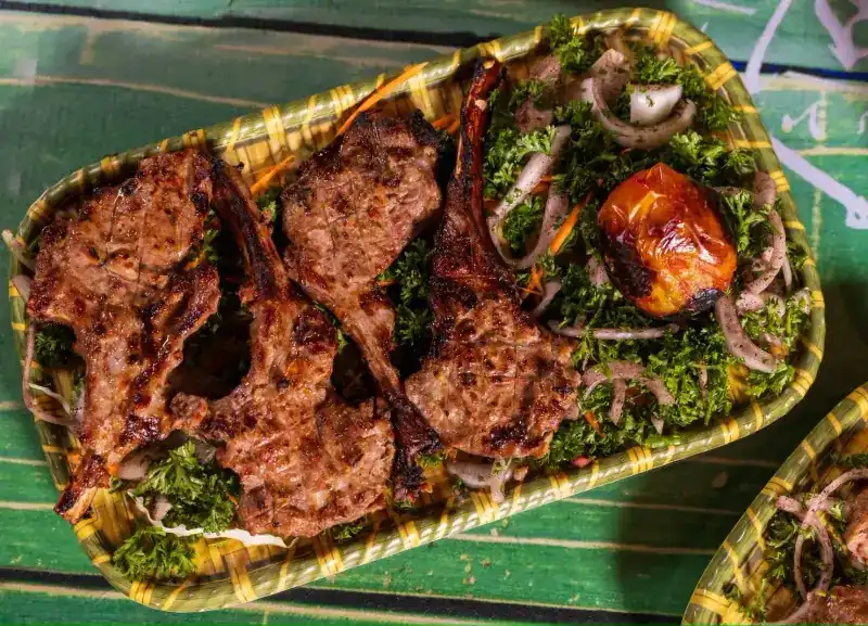 Grilled lamb chops on parsley and onion with a roasted tomato