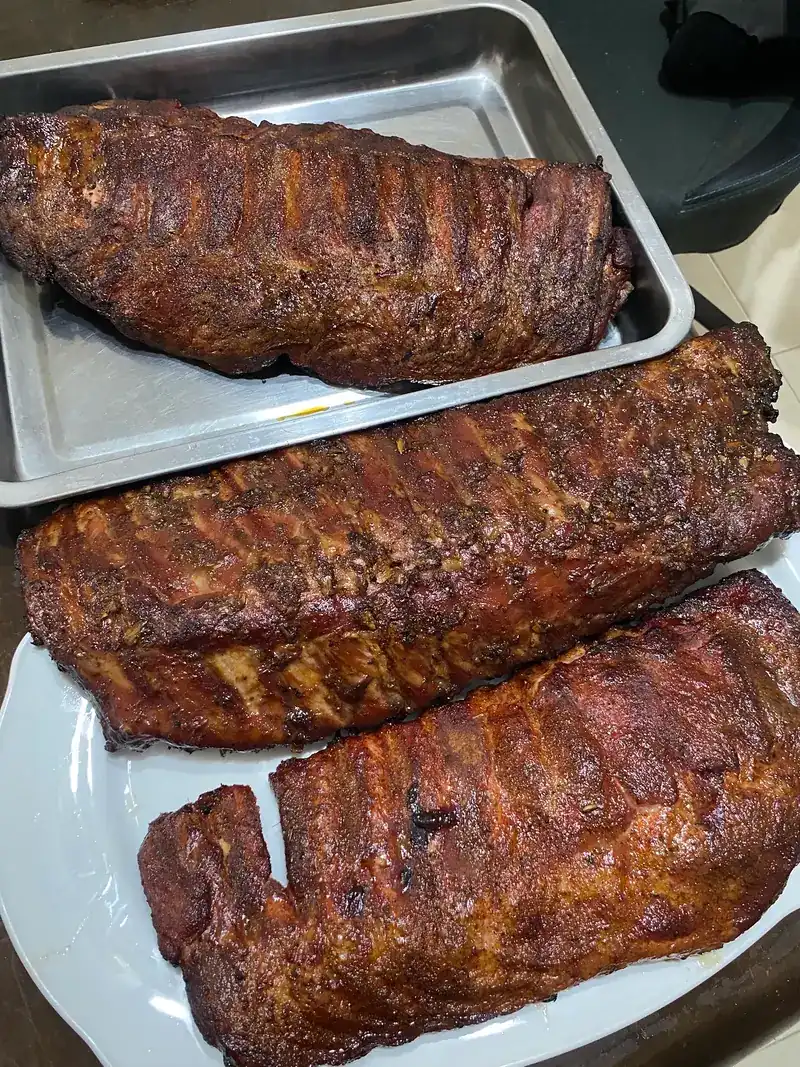 Three racks of smoked ribs on a tray and a plate