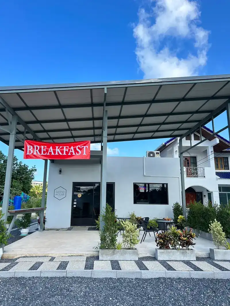 The café from the road: a white building under a steel canopy, a red Breakfast banner and tables outside