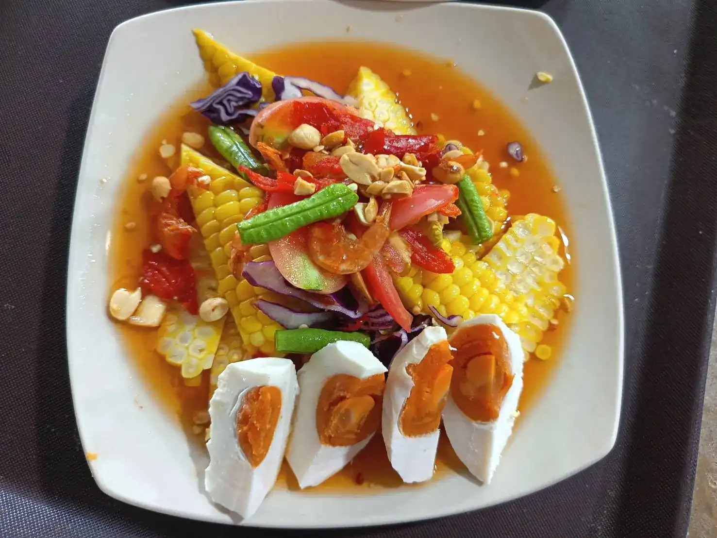 Spicy corn salad with salted egg, tomato, long beans and peanuts / ตำข้าวโพดไข่เค็ม ใส่มะเขือเทศ ถั่วฝักยาว และถั่วลิสง
