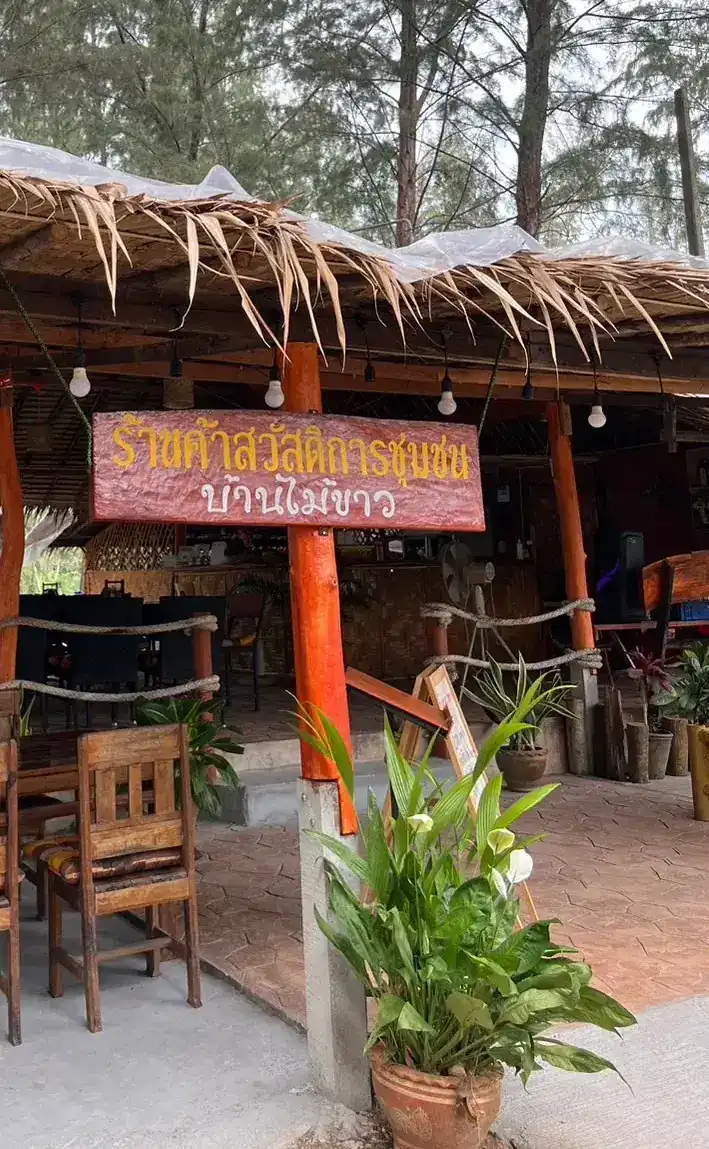 The red signboard under the thatched roof, reading Ban Mai Khao community welfare shop