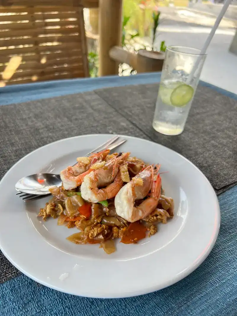 Whole prawns over a stir-fry, with a cold drink and lime