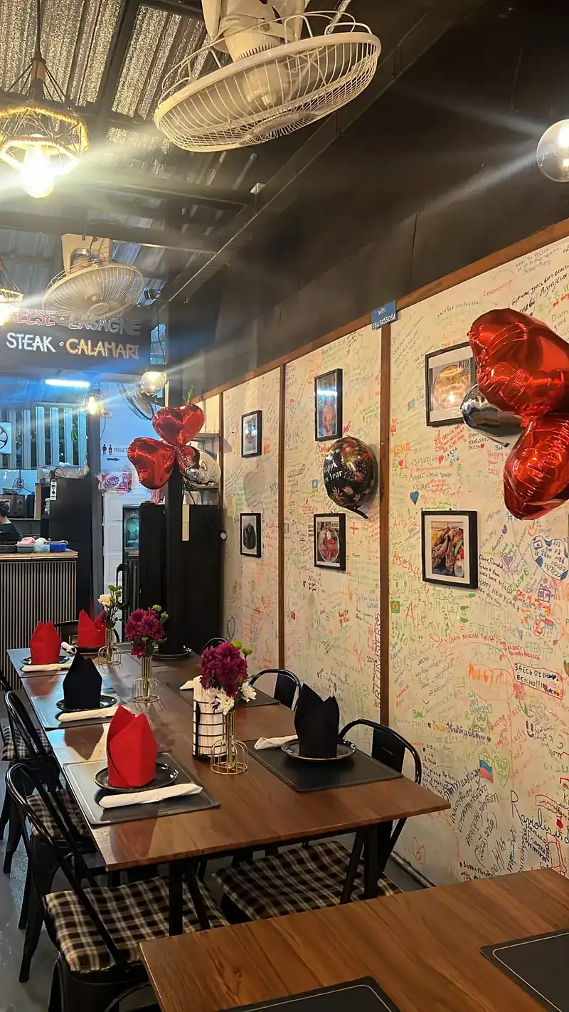 Inside: tables laid with folded napkins, framed pictures, and walls covered in handwritten notes