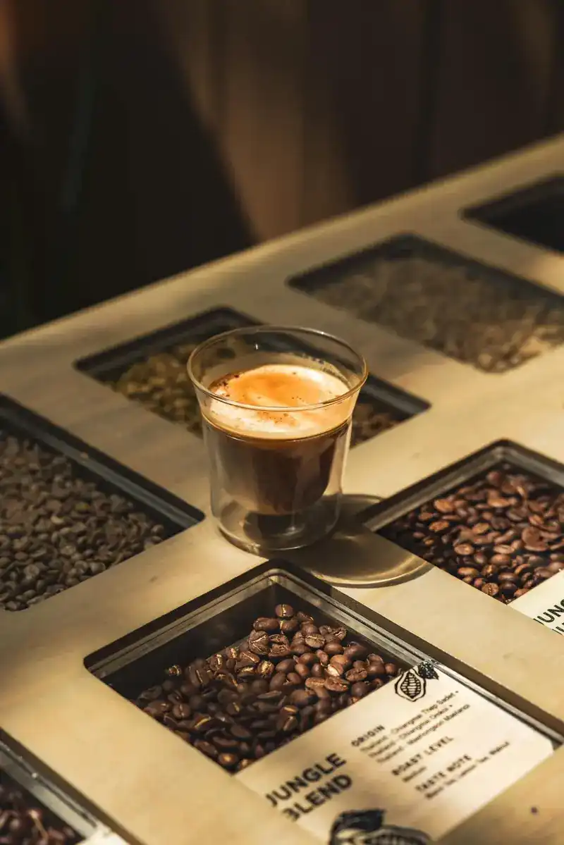 A glass of espresso on a table inlaid with coffee beans