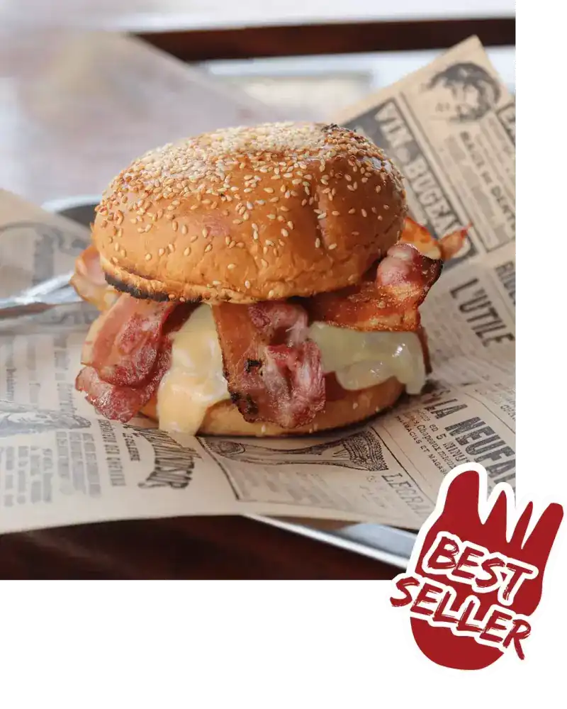 A sesame bun with bacon and melted cheese on printed paper