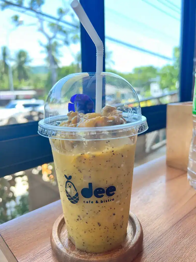 An iced fruit drink in a dee cup on the window ledge