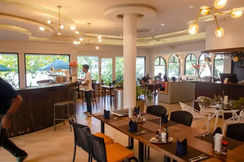 The dining room: long wooden tables, a bar counter and windows on the lake