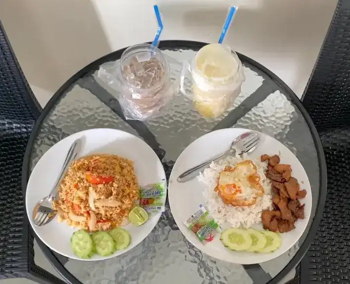Fried rice and rice with a fried egg and pork on a glass table, with two iced drinks — ข้าวผัดและข้าวไข่ดาวกับหมูบนโต๊ะกระจก พร้อมเครื่องดื่มเย็นสองแก้ว