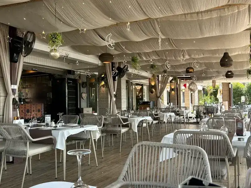 The long dining room under the canvas in the evening, tables set with white cloths and glasses