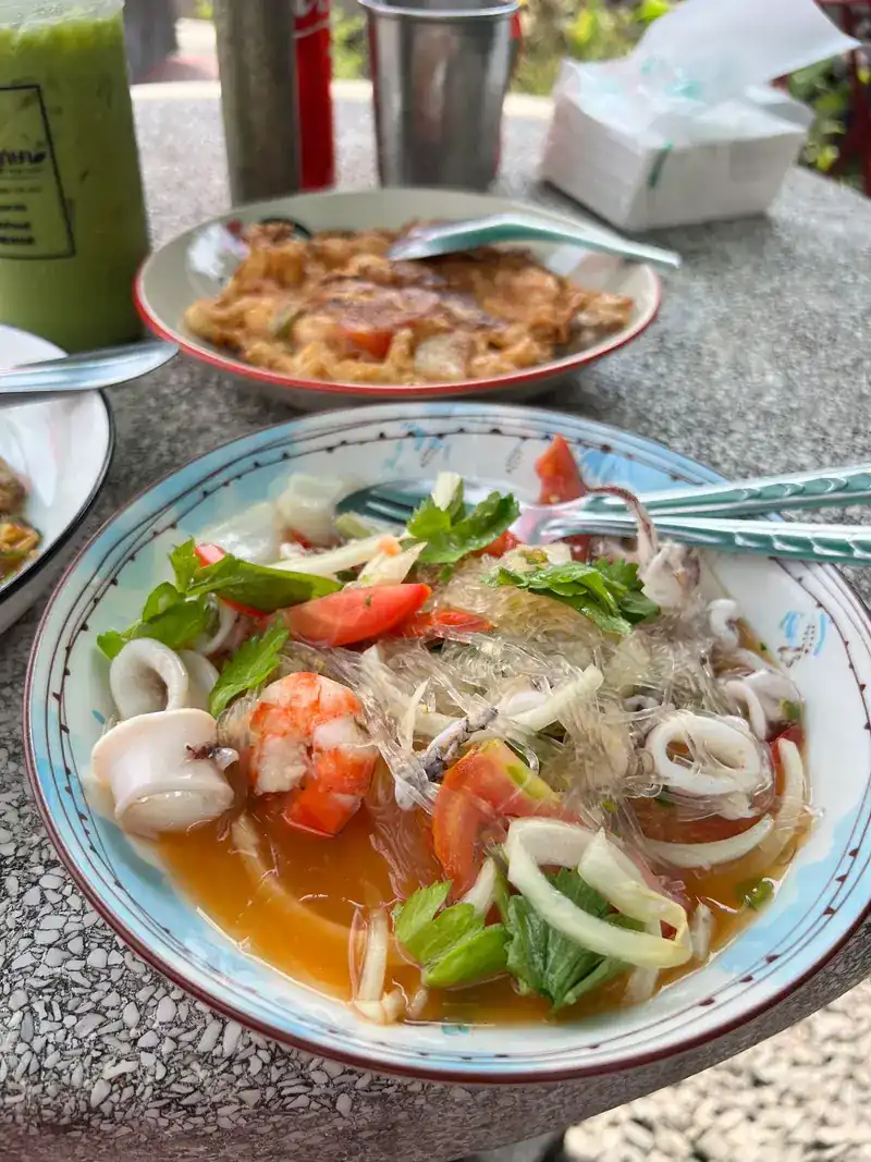 Glass-noodle soup with squid, prawns, tomato and herbs in a patterned bowl
