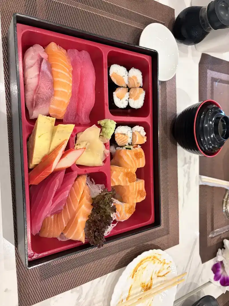 Sashimi bento in a red lacquer tray with tuna, salmon, tamago and maki