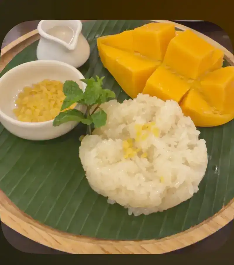 Mango with sticky rice and coconut cream on a banana leaf
