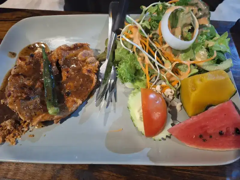 Pork steak in brown sauce with okra, salad, tomato, pumpkin and watermelon