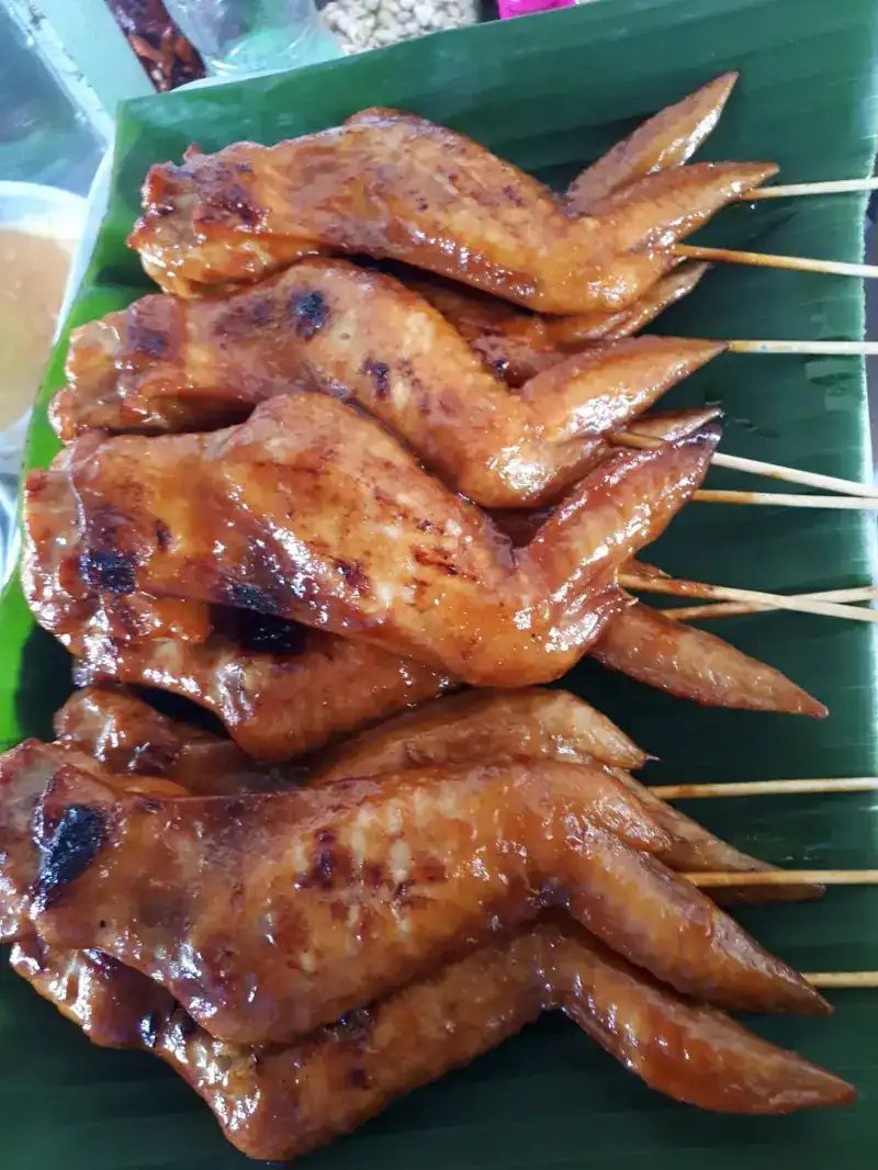 Grilled chicken wings on skewers, laid on a banana leaf