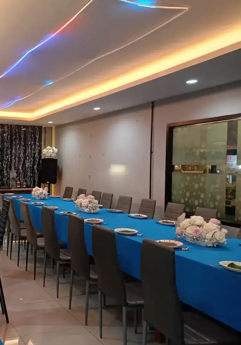 The air-conditioned room, laid with long tables in blue cloths and flowers