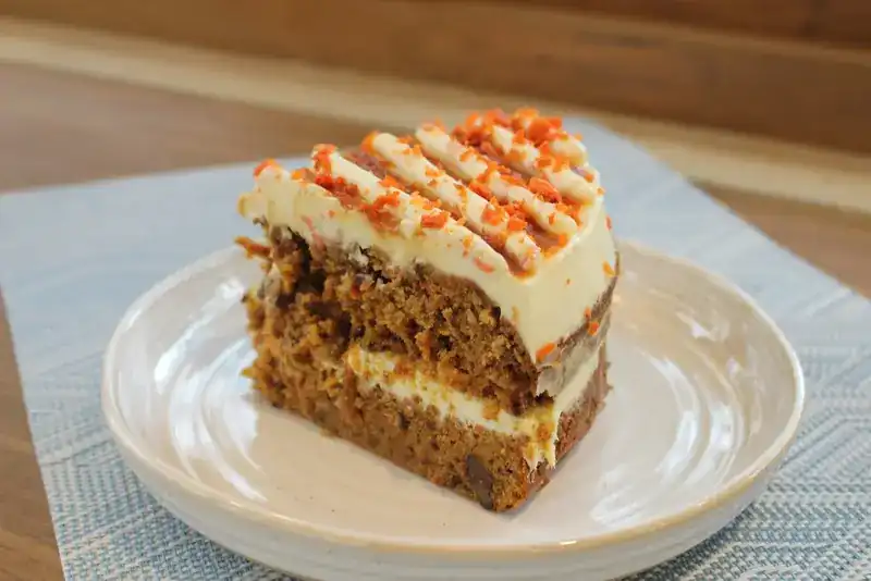 A slice of carrot cake with a creamy frosting