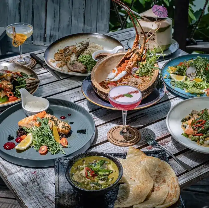 A weathered wooden table on the deck covered with plates, bowls and glasses