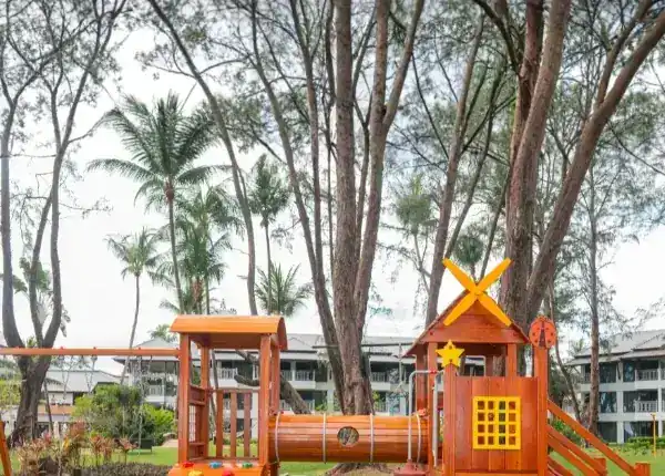 Wooden climbing frame and play tunnel under tall trees