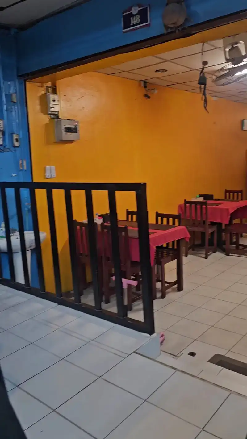 The doorway of number 148: a blue frame, yellow walls and red tablecloths inside
