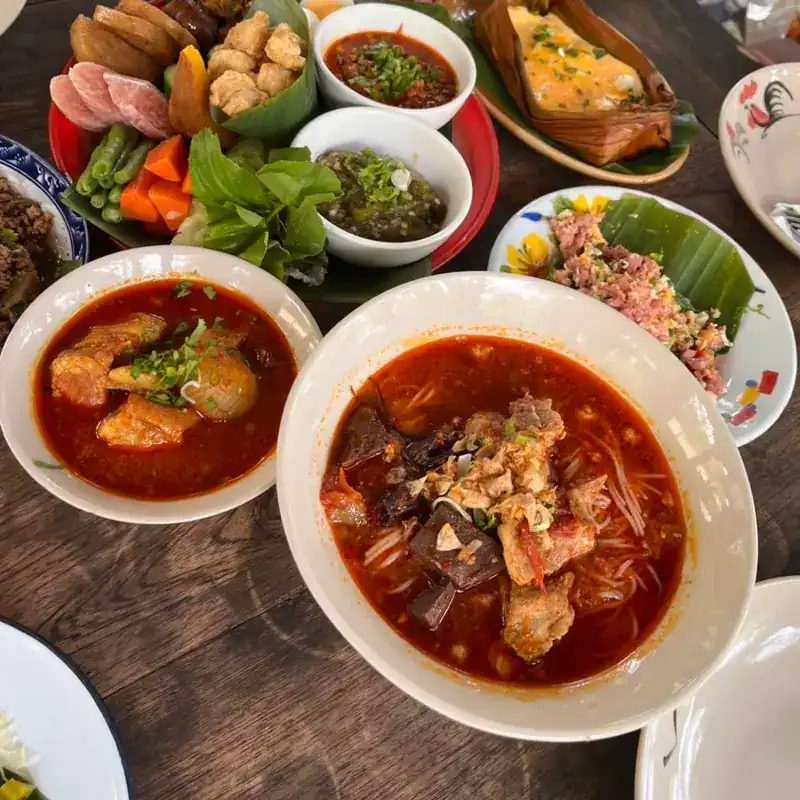 A table of northern dishes with two bowls of noodles in red broth